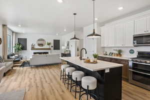 Kitchen featuring stainless steel appliances, a breakfast bar, white cabinets, open floor plan, and recessed lighting