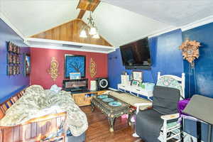 Living area featuring crown molding, lofted ceiling, dark wood-style floors, and a chandelier
