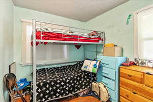 Bedroom with a textured ceiling and wood finished floors