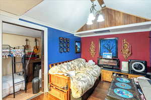 Bedroom featuring wood finished floors, a chandelier, and lofted ceiling