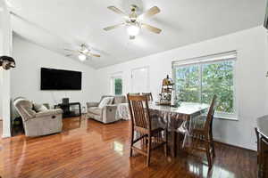 Dining area with vaulted ceiling, dark wood-style floors, and ceiling fan