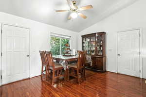 Dining room featuring dark wood finished floors, lofted ceiling, and a ceiling fan