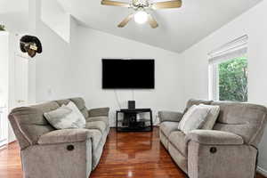Living area with vaulted ceiling, wood finished floors, and a ceiling fan