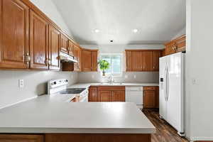 Kitchen featuring brown cabinets, white appliances, light countertops, and recessed lighting