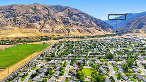 Aerial view of property and surrounding area featuring nearby suburban area and a mountain backdrop
