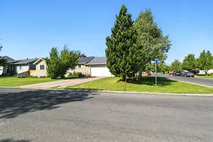 view of property featuring a front lawn, an attached garage, and driveway