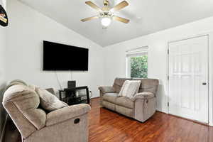 Living area featuring vaulted ceiling, dark wood-type flooring, and a ceiling fan