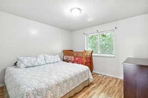 Bedroom with light wood-type flooring and a textured ceiling