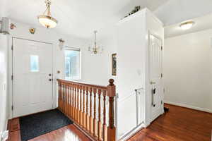Foyer entrance with dark wood finished floors and a chandelier