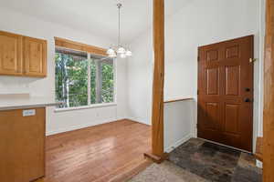 Unfurnished dining area featuring a chandelier, dark wood-style floors, and vaulted ceiling