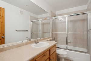 Bathroom with shower / bath combination with glass door and vanity