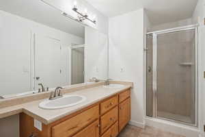 Bathroom with a shower stall, double vanity, and light tile patterned floors