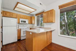 Kitchen featuring white appliances, healthy amount of natural light, light countertops, and a peninsula