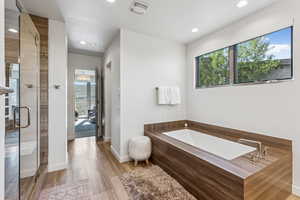 Bathroom featuring recessed lighting, a garden tub, a stall shower, and wood finished floors
