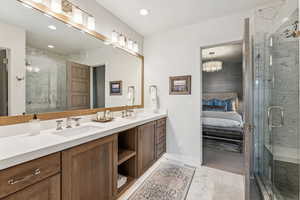 Bathroom with double vanity, a marble finish shower, ensuite bathroom, and recessed lighting