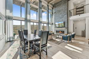 Dining area featuring a stone fireplace, wood tiled floors, beam ceiling, a high ceiling, and recessed lighting