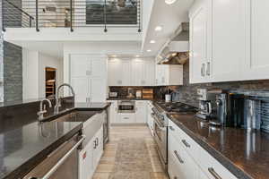 Kitchen featuring appliances with stainless steel finishes, recessed lighting, wall chimney exhaust hood, white cabinetry, and tasteful backsplash