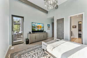 Bedroom featuring a towering ceiling, carpet floors, access to outside, beam ceiling, and a chandelier