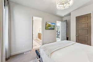 Carpeted bedroom with a chandelier and ensuite bathroom