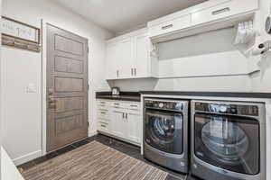 Laundry area with washer and dryer, cabinet space, and wood tiled floors