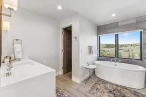 Full bathroom with a freestanding bath, wood finished floors, recessed lighting, and vanity