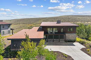 View of front of house featuring stone siding, a chimney, and concrete driveway