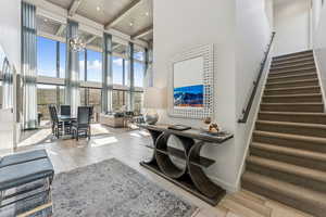 Living area featuring wood tiled floors, beam ceiling, a chandelier, a towering ceiling, and stairs