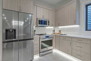 Kitchen with appliances with stainless steel finishes, light brown cabinetry, and modern cabinets