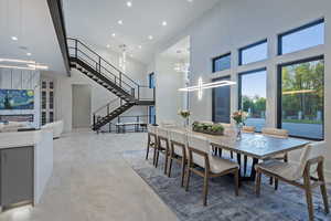 Dining area with a towering ceiling, recessed lighting, stairs, and a chandelier