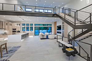Living area featuring a high ceiling, recessed lighting, and stairs