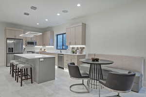 Kitchen featuring light brown cabinets, a breakfast bar, appliances with stainless steel finishes, a kitchen island, and recessed lighting