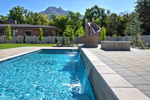 View of swimming pool with a fenced backyard, a water slide, a mountain view, and a patio