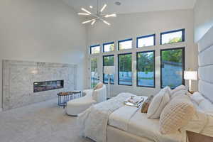 Bedroom featuring a high end fireplace, high vaulted ceiling, carpet floors, and a chandelier