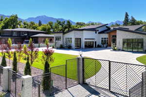 Modern home with stone siding, a fenced front yard, a mountain view, an attached garage, and driveway