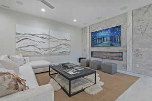 Living room featuring a large fireplace, recessed lighting, and tile walls