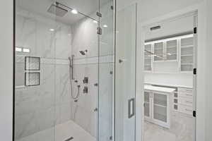 Full bathroom featuring a marble finish shower and a walk in closet