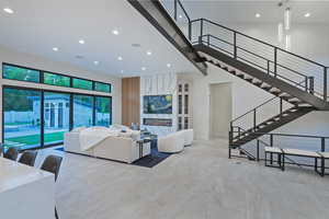 Living room featuring recessed lighting, a high ceiling, and stairs