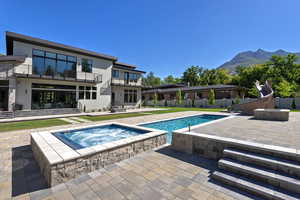 View of pool with a patio, a water slide, a balcony, a fenced backyard, and a pool with connected hot tub