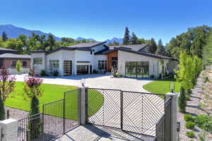 Contemporary home with stone siding, a fenced front yard, curved driveway, and a mountain view