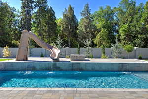 View of swimming pool featuring a water slide, a fenced backyard, and a patio area