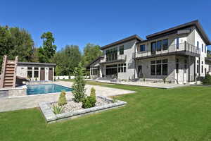 Rear view of property featuring a patio area, stucco siding, a balcony, stone siding, and a yard