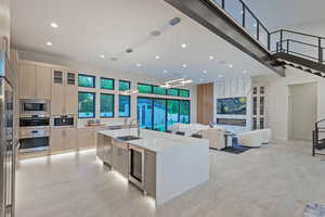 Kitchen with pendant lighting, light stone countertops, open floor plan, recessed lighting, and glass insert cabinets