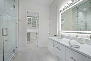 Bathroom featuring double vanity, a marble finish shower, light marble finish flooring, and a spacious closet
