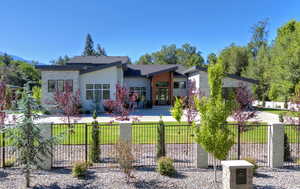 View of front facade with stone siding, stucco siding, and a fenced front yard