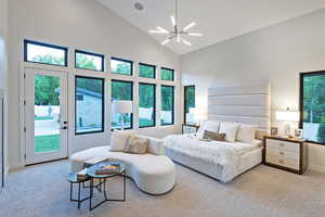Carpeted bedroom with high vaulted ceiling, access to exterior, and a chandelier