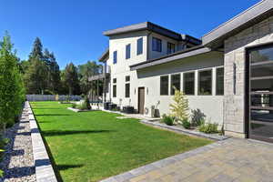 Back of property with stone siding, a patio, a balcony, and stucco siding