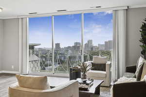 Living area with a wall of windows, a skyline view, plenty of natural light, and wood finished floors