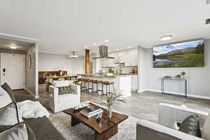 Living area with light wood-style flooring, crown molding, and recessed lighting