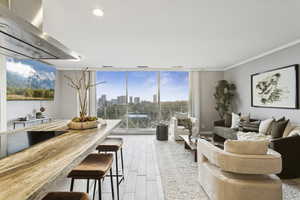 Living area with a skyline view, expansive windows, light wood finished floors, recessed lighting, and crown molding