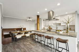 Kitchen with backsplash, white cabinets, island exhaust hood, recessed lighting, and light stone countertops